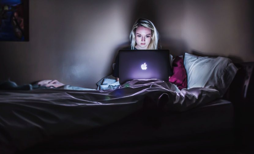 Photo d'une femme dans son lit avec son ordinateur